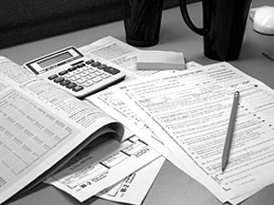 Image of tax forms, calculator, pencil and coffee cops