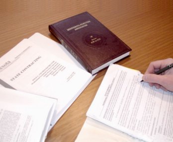 Image of Minnesota Statutes book and someone completing contract form